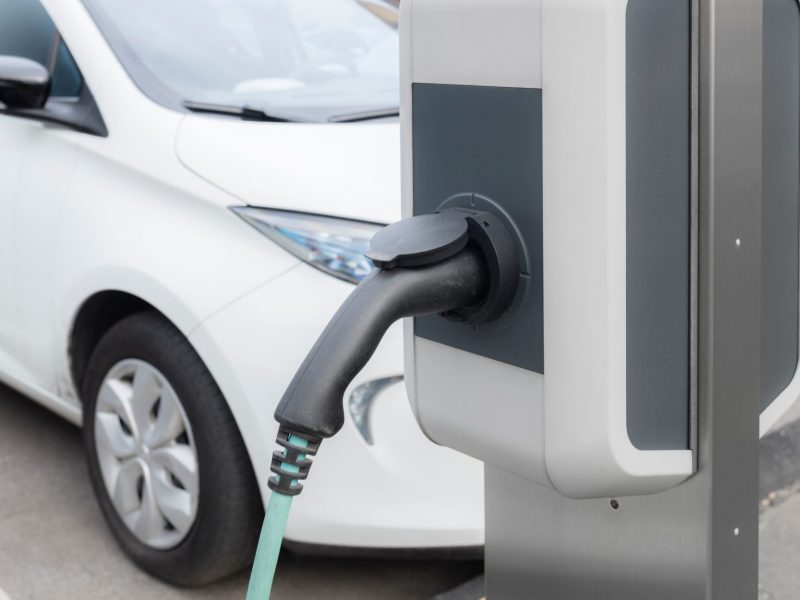Ladesäule für Elektroautos. Im Hintergrund steht ein geparktes Auto.